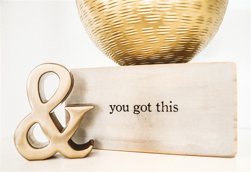 Wooden sign that says "you got this" with a gold ampersand decor item to the left