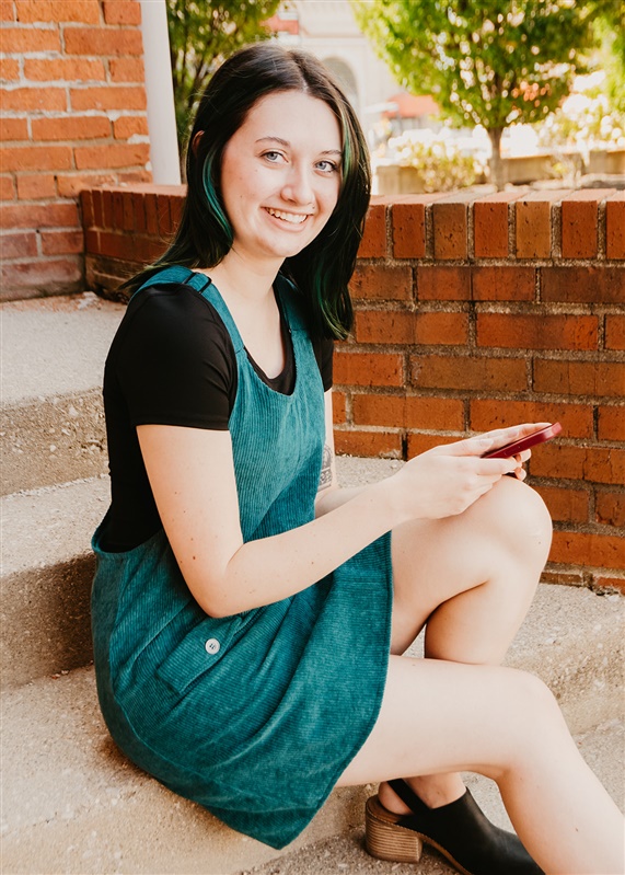 Haven Collective Community Manager, Jenna Brooks on Mansion steps working on iPhone